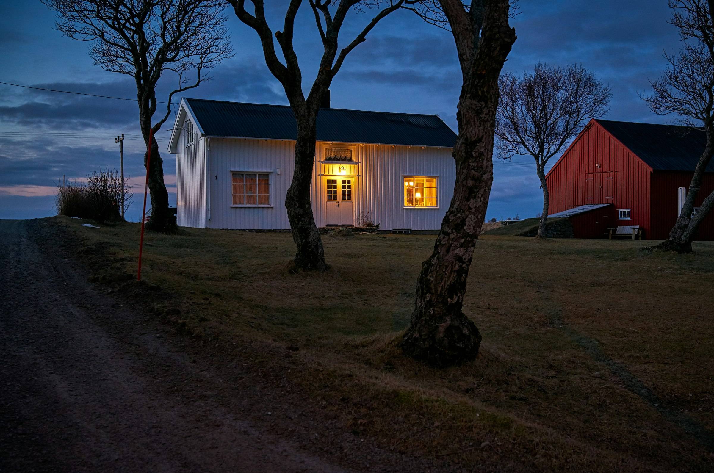 Hvitt trehus med lys i vinduene i blåtimen, Vesterålen